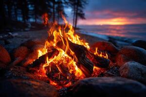 Fire crackles by the water during sunset, surrounded by smooth s photo