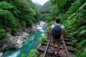 Man explores abandoned train tracks by a river in a lush foreste photo
