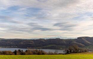 The river Rhine flows among the hills and meadows under the even photo