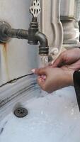 Washing hands at a public fountain in a busy area video