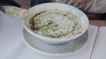 Enjoying a bowl of yogurt soup with fresh herbs and spices video