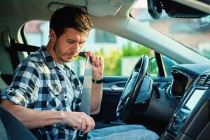 Man fastening seat belt inside car before driving photo