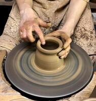 Hands of master shape clay pot on a potters wheel. Closeup. photo