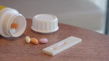 Pills and a pregnancy test kit are displayed on a wooden surface indoors video
