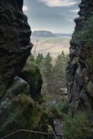 View into a rocky gorge with a wooded valley and hills in the background photo