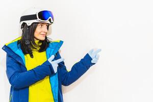 Snowboarder happy woman wear blue suit goggles mask hat ski padded jacket show fingers up right to copy empty space isolated on plain pastel pink background. Winter sport promotion banner empty space photo