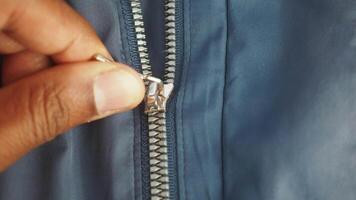 Close up of a sturdy zipper on a blue jacket fabric video