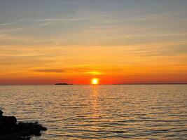Serene sunset over the sea. The sun sets on the water. The sky is painted with bright colors. Sunny path on the water. Summer evening et sunset beach. photo