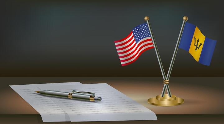 USA and Barbados flags on table in office. International relations on a dark gradient color background.