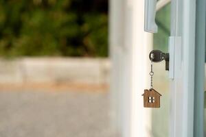 Landlord key for unlock house is plugged into the door. Second hand house for rent and sale. keychain is blowing in the wind. mortgage for new home, buy, sell, renovate, investment photo