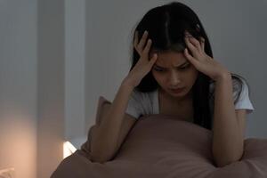 asian woman in bed late trying to sleep suffering insomnia, sleepless or scared in a nightmare, looking sad worried and stressed. Tired and headache or migraine wake up in the middle of the night photo