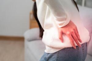 woman holding lower back while and suffer from unbearable pain health and problems, chronic back pain, backache in office syndrome, scoliosis, herniated disc, muscle inflammation. photo