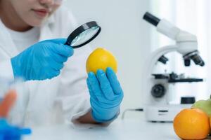 Scientist use magnifying glass to check physical occur from chemical on fruit and vegetable residues in laboratory. inspect the concentration of chemical residues, standard find prohibited substances photo