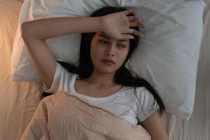 woman in bed late trying to sleep suffering insomnia, sleepless or scared in a nightmare, looking sad worried and stressed. Tired and headache or migraine waking up in the middle of the night photo