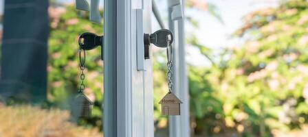 Landlord key for unlock house is plugged into the door. Second hand house for rent and sale. keychain is blowing in the wind. mortgage for new home, buy, sell, renovate, investment, owner, estate. photo