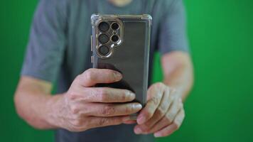 a young man taking photo or a clip media with his smartphone, on chroma key green screen, close-up, hand are using a phone, take a photo and mobile phone video
