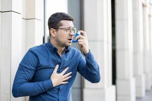 A man uses an inhaler, highlighting respiratory distress and healthcare solutions in an urban setting. photo