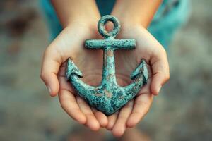 Child holding a small weathered anchor in open hands photo