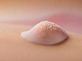 Close-up of a pink, textured substance on skin, with granular details. photo