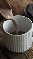 Vertical . Cocoa or hot chocolate pouring into mug on rustic wooden background video