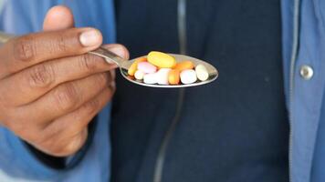 Holding a spoonful of colorful pills in focus video