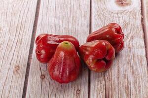 Three red fruits on a wooden table photo