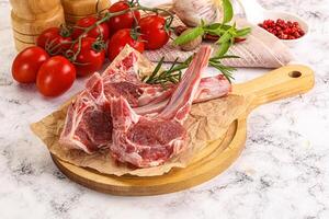 A cutting board with two lamb chops and tomatoes photo