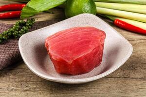 A piece of raw tuna sitting on a plate next to some vegetables photo