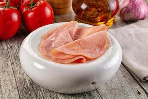 Ham slices in a bowl on a wooden table photo