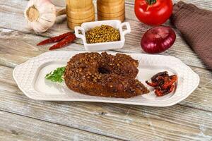 A plate with a meat dish on it and some spices photo