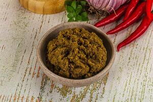 A bowl of curry paste with a red onion and a green pepper photo