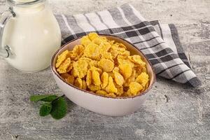 Corn flakes and milk on a rustic table photo
