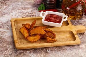 A wooden cutting board with some fries and ketchup photo