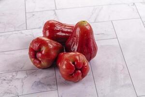 Three red peppers sitting on a marble counter photo