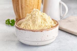 A bowl of flour next to a jug of milk photo
