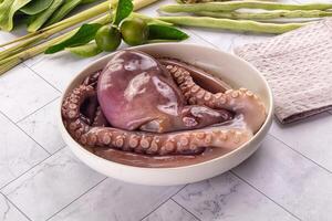 A bowl of octopus sitting on a counter next to some green beans photo