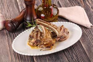 A plate with a lamb rack on it and a bottle of olive oil photo