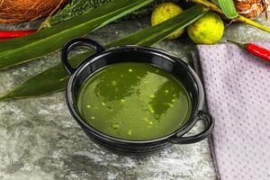 A bowl of green soup with a coconut and some other vegetables photo