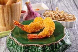 Fried shrimp on a green plate with chopsticks and a bowl of noodles photo
