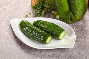 A white plate with cucumbers and a jar of pickles photo