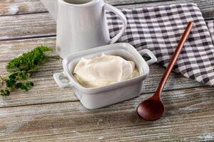 Yogurt in a bowl and spoon on a wooden table photo