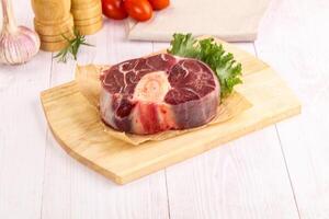 Raw beef on wooden cutting board with vegetables and herbs photo