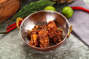 A bowl of chicken wings with a coconut and some peppers photo