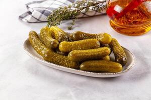 Pickles in a bowl on a table with a glass of whiskey photo