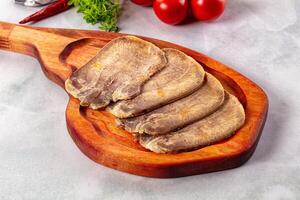 A wooden cutting board with some meat on it photo