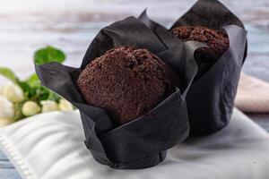 Two chocolate muffins sit on a table photo