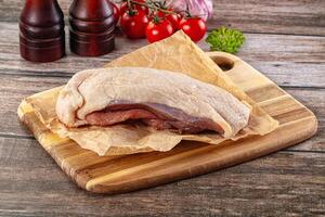 A piece of meat on a cutting board with a bottle of ketchup and tomatoes photo