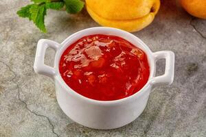 A white cup with jam and some peaches photo