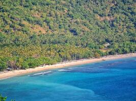Tropical Island Beach with Turquoise Water and Lush Green Vegetation View photo