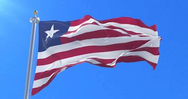 Flag of Liberia waving at wind with blue sky in slow loop video